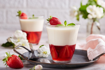 Layered dessert in glass with vanilla panna cotta and jelly with strawberries