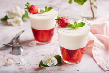 Layered dessert in glass with vanilla panna cotta and jelly with strawberries