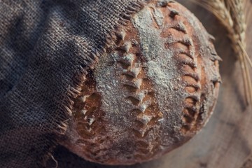 Homemade lined brown bread with a hessian fabric on a wooden log service plate, close up