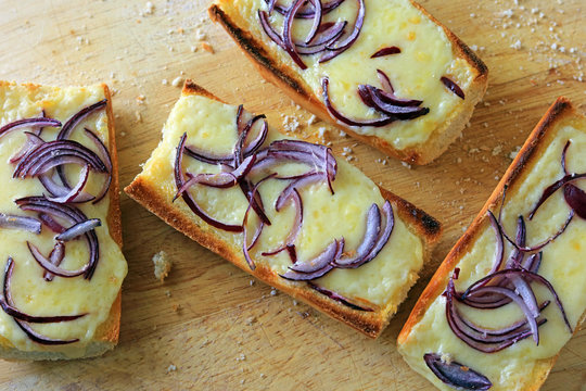 Sliced sweet red onions on melted cheddar cheese served on toasted fresh baguette.