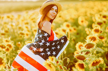 4th of July. Amazing girl in hat with the American flag in a sunflower field. Freedom day. Sunset...