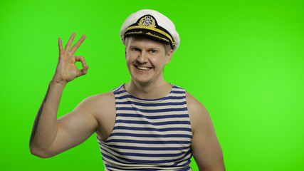 Young sailor man shows ok sign, looking at camera. Seaman guy in sailor's vest