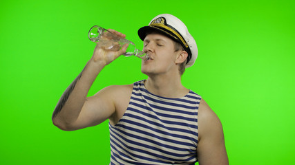 Young sailor man drinks vodka. Seaman guy in sailor's vest shirt. Chroma key