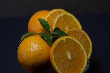 Sliced orange in glass bowl on dark background
