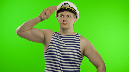 Young sailor man salutes with hand, looking up. Seaman guy in sailor's vests