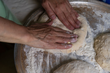 Hands are processing dough for baking.