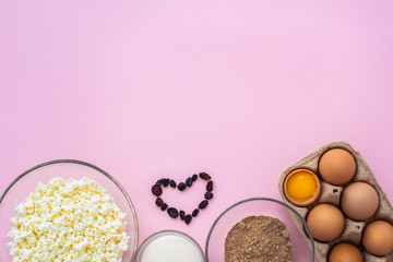 on a pink background, products for the preparation of casserole cottage cheese. Eggs, cottage cheese, raisins, sugar, butter, flaxseed flour. household chores. stay home. recipe. Copyspace. Flat lay