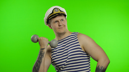 Sailor man making weightlifting with dumbbell. Seaman guy in sailor's vest