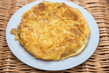 potato omelette on white plate with a vintage wicker background