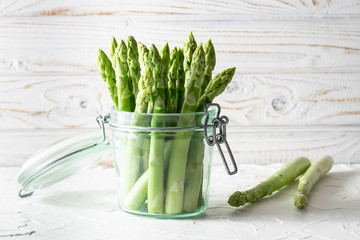 Organic raw green asparagus in a glass jar on white wooden background close up. healthy diet food concept. - Powered by Adobe