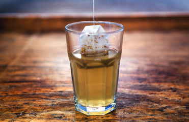 close-up of glass with teabag on rustic wooden table