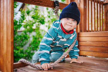 little boy with down syndrome plays on the playground