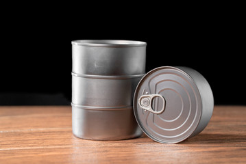 column of tuna products silver color and one lying on brown wooden table and dark background