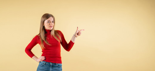 Smiling woman pointing finger. Isolated portrait of female business model on yellow background, banner size