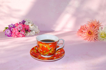 A cup of tea and flowers on a sunny table with long shadows, a bouquet of spring flowers for mood, minimal concept of a healthy lifestyle and beauty, creative composition of home comfort