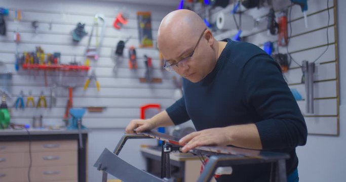 Professional craftsman checks how refurbished and waxed skis are. Ski readiness for the winter season. Professional workshop for the repair and maintenance of winter sports equipment.