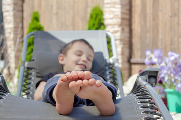 the boy's bare feet on the chaise longue. resting boy in the sun. The concept of relaxation. © Ekaterina