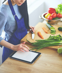 Young woman cutting vegetables in kitchen at home