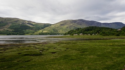 Fototapeta na wymiar Panoramic view of a lake with green hills on the background, Glencoe, Scotland 