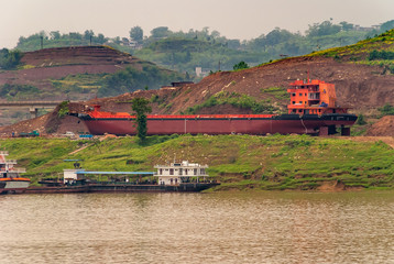 Myaoyinan, Chongqing, China - May 8, 2010: Yangtze River. Red carcass of large river boat under...