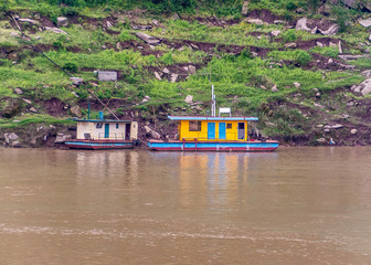 Myaoyinan, Chongqing, China - May 8, 2010: Yangtze River. 2 colorful house boats moored along green...