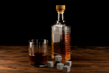 Glass of Irish whiskey with glass bottle over dark background.