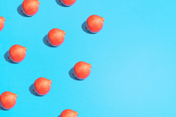 red pomegranate pattern on bright light blue background. Minimal flat lay food texture. Summer abstract trendy fresh concept.