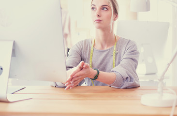 Fashion designer woman working in studio, sitting at thhe desk