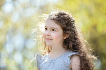 Portrait of a smiling girl with curly hair in the sun.