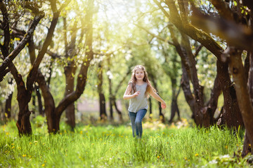 Fototapeta na wymiar Little girl among the trees in the sun