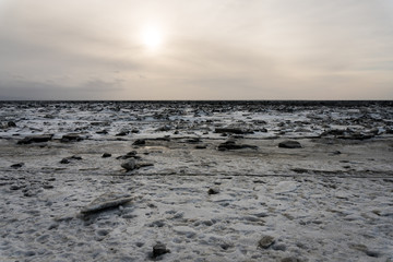 Frozen beach with its ice breaking and melting on the coast of Anchorage, Alaska. Instead of sand, there's snow, ice and rocks. Beautiful landscape showing global warming and climate change. Kincade.