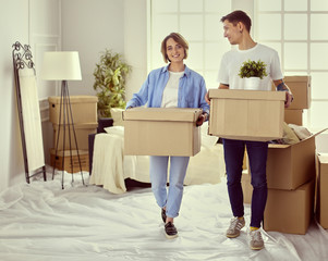 A girl and a guy holding boxes for moving the hands and looking inside box