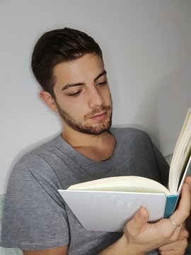 Bel ragazzo legge un libro a letto