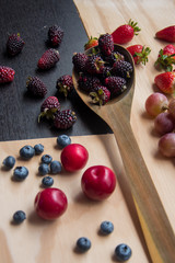 Naklejka na ściany i meble Blackberries and red fruits on a wooden surface