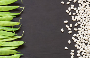 Uncooked dried white haricot beans with fresh raw green beans pod plant on rustic table. Heap of...