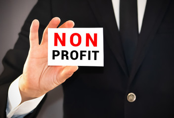 Businessman Holding Small White Signage Showing Non Profit Texts.