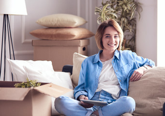 Smiling young woman lying on sofa in new apartment