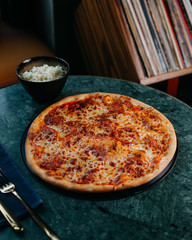 a top view pizza tasty salted with cheese on the green table
