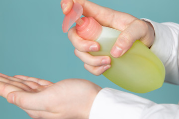 a front view green spray young man using spray to desinfect his hands on the blue floor