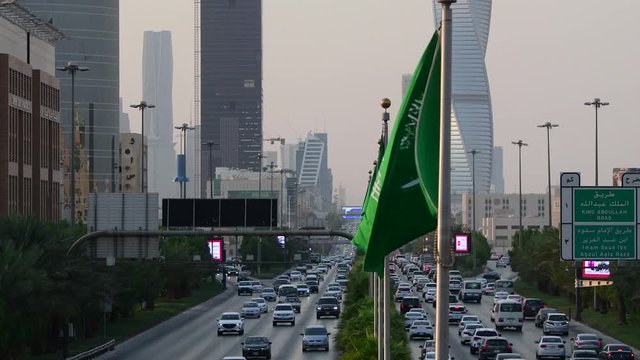 Saudi Arabia national flag waving and Riyadh's main street (King Fahd Road) on the background
