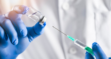 Vaccine dose detail in doctor hands with blue gloves. Vaccination hypodermic injection treatment care in hospital prevention illness or coronavirus