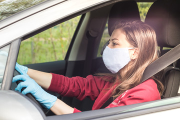 girl in medical mask and gloves driving a car. personal protective equipment during the period of coronavirus, epidemic. young woman takes care of her health while traveling