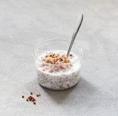 Buckwheat boiled with milk in a glass Cup on a light gray background
