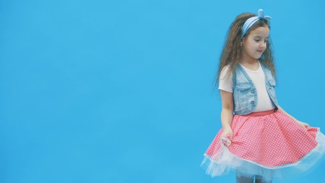 LIttle girl standing over blue background in 4k slowmotion video.