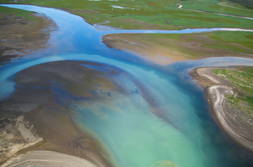 Turquoise, blue, green, river flowing smoothly through dirt waterway in Alaska