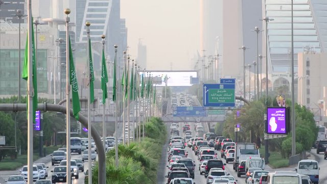 Saudi Arabia national flag waving and Riyadh's main street (King Fahd Road) on the background