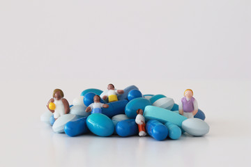 Small figurines among blue pills in selective focus