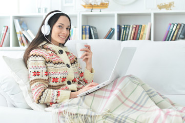 Young beautiful woman with laptop on sofa at home