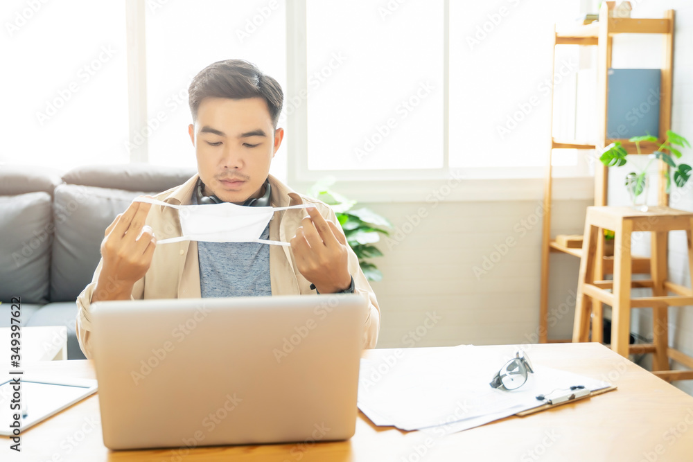 Fototapete Asian man putting on protective mask Working from home web designing graphical user interface UX UI, in home office using computer laptop designing creative planning innovative idea, in quarantine