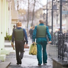 Armed Cash-in-transit guard walking with money bags walking down the street. Cash collectors carry...